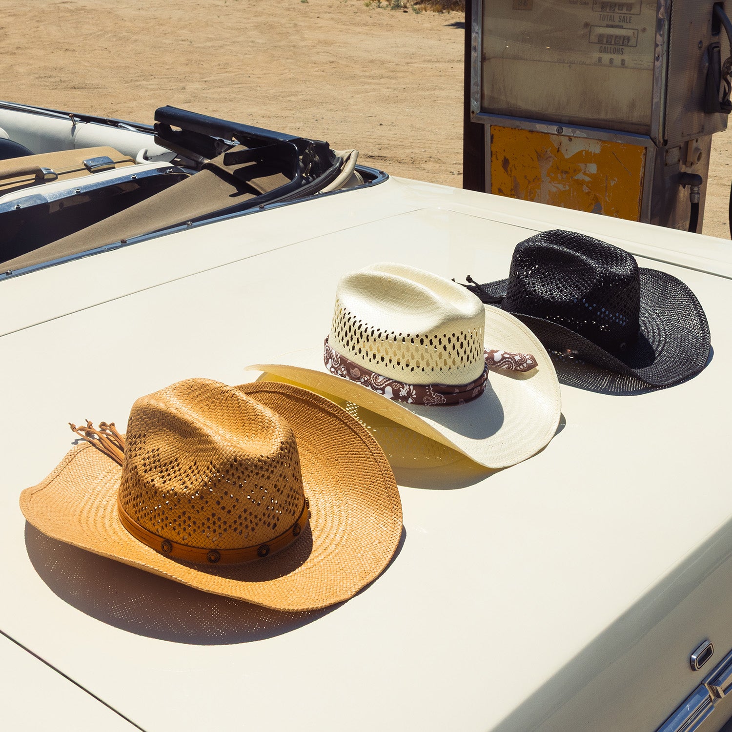 Four cowboy hats on a car hood with a truck in the background