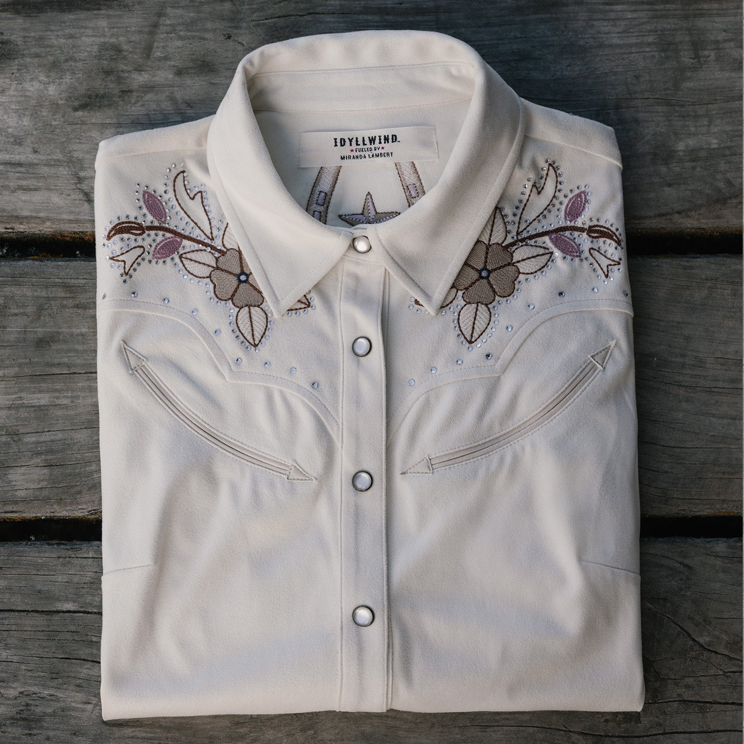 Folded white shirt with floral embroidery on a wooden surface