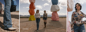Three people standing in front of colorful rock formations in a desert landscape.
