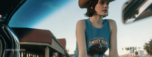 Person wearing a 'Sweet Tea' tank top with a cowboy hat in an urban setting