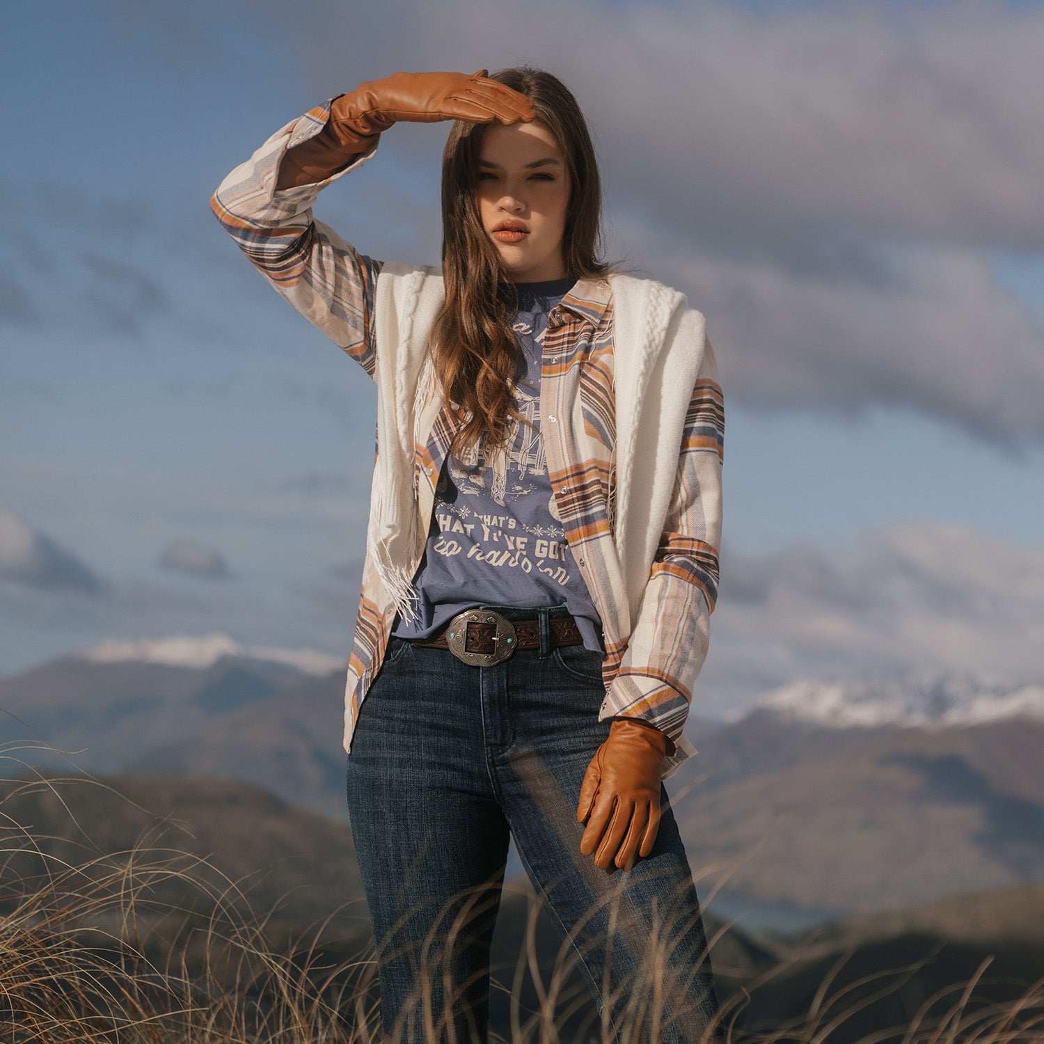 Woman standing in a scenic outdoor setting with mountains in the background